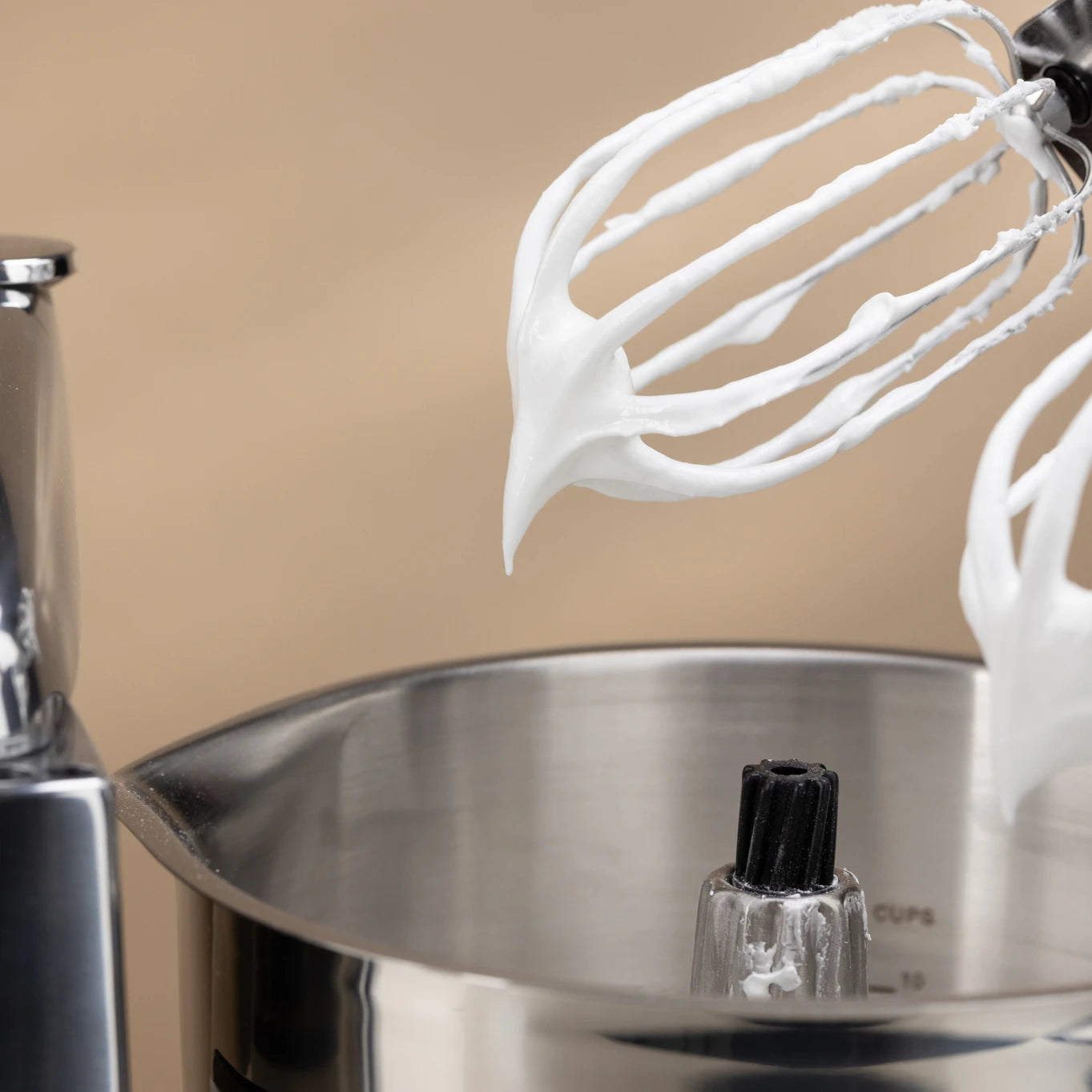 The Kitchen Table Ankarsrum stainless steel beater bowl with balloon whisks covered in fluffy whipped meringue.