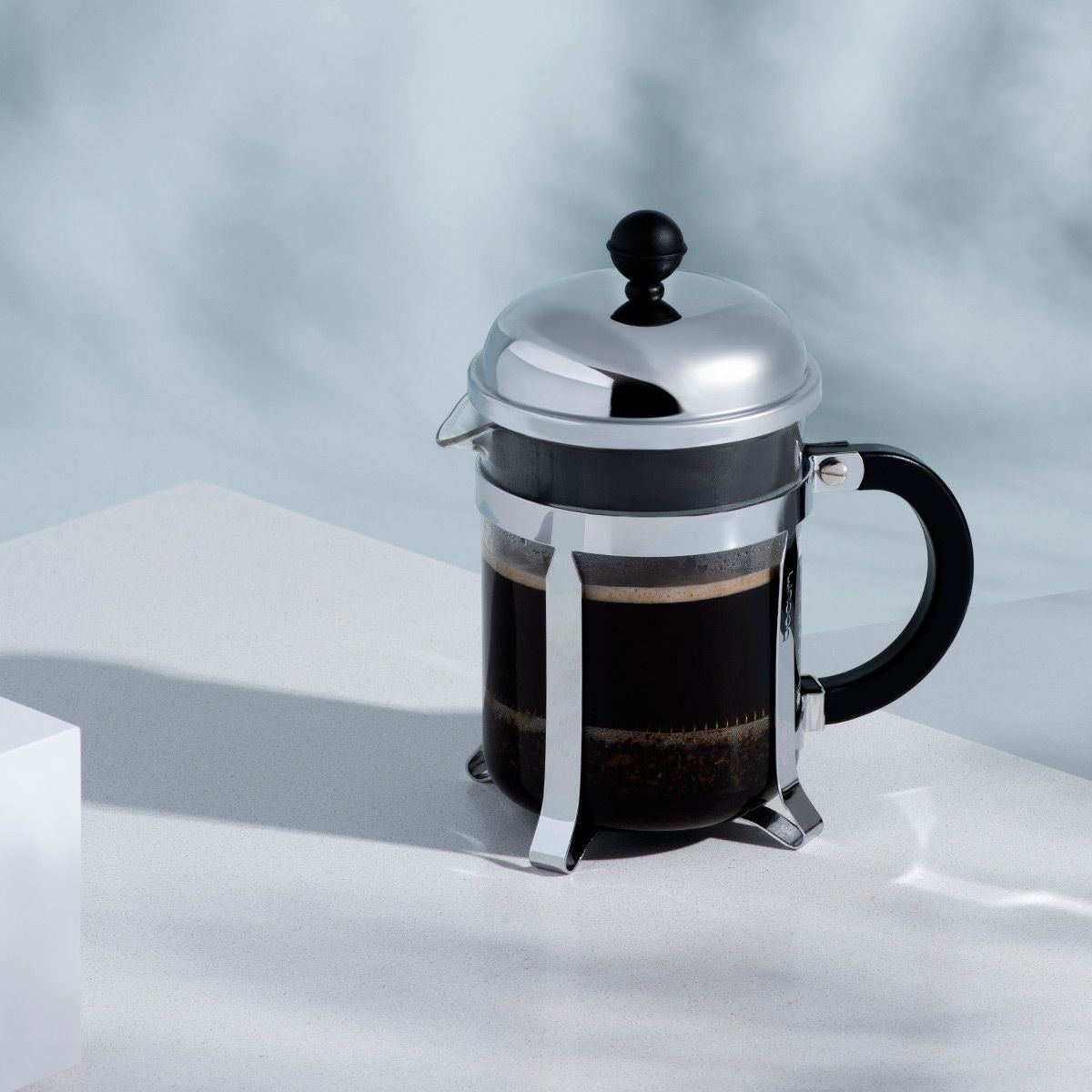 The Kitchen Table Bodum Chambord 4-cup French press coffee maker with glass carafe and polished chrome frame.