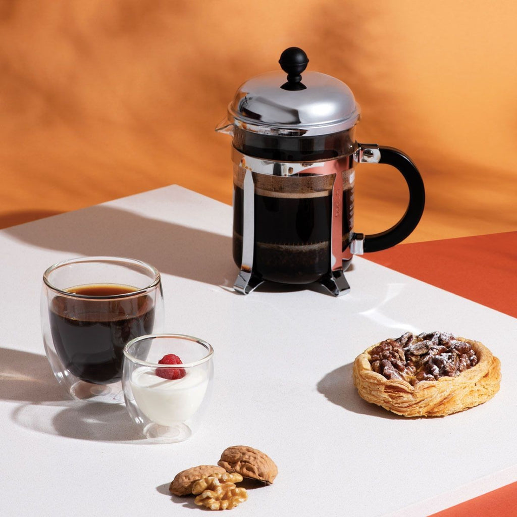 The Kitchen Table Chambord 4-cup French press coffee maker with glass carafe and stainless steel frame on a table