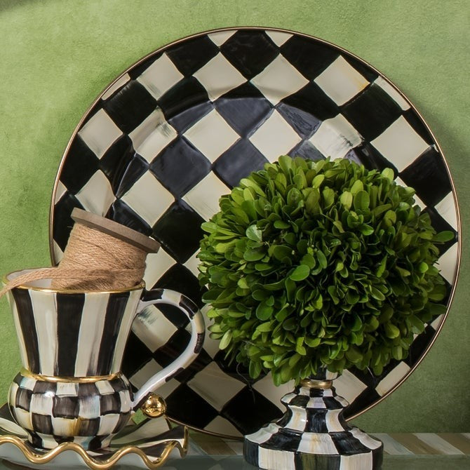 The Kitchen Table Courtly Check enamel charger plate with black and white hand-painted pattern and bronze rim.