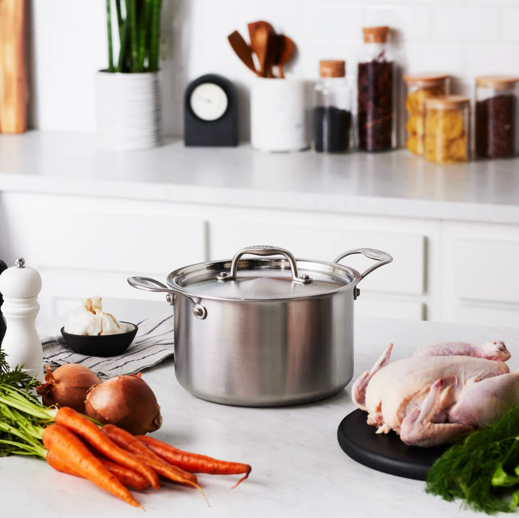 The Kitchen Table EATER 5 quart stainless steel sauce pot with lid on a kitchen counter with fresh vegetables.