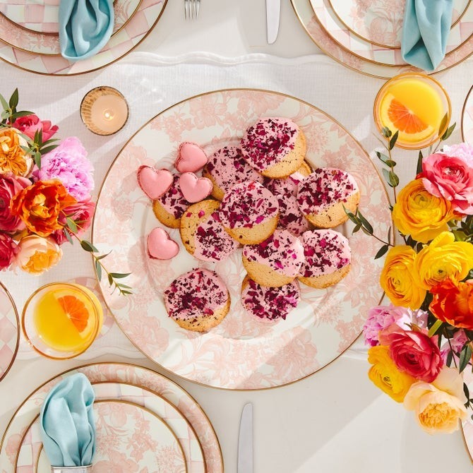 The Kitchen Table floral dinner plate topped with pink-frosted cookies and heart-shaped macarons on a decorated table