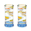 The Kitchen Table Go Fish highball glasses featuring colorful fish patterns, navy striped bases, and gold rim trim.