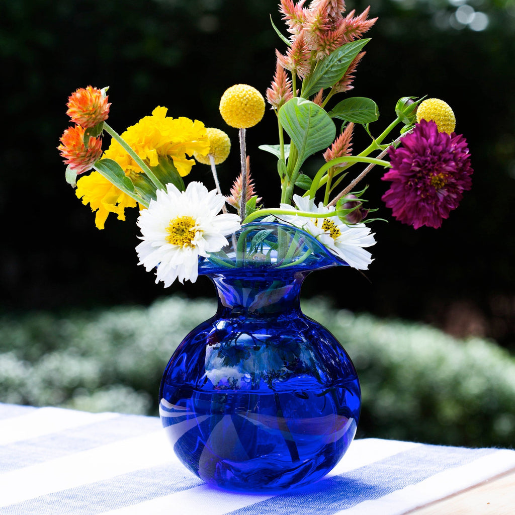 The Kitchen Table mouthblown blue glass fluted bud vase filled with a vibrant bouquet of colorful garden flowers.