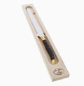 The Kitchen Table Jean Dubost Laguiole bread knife with a black handle, brass accents, and serrated stainless blade.