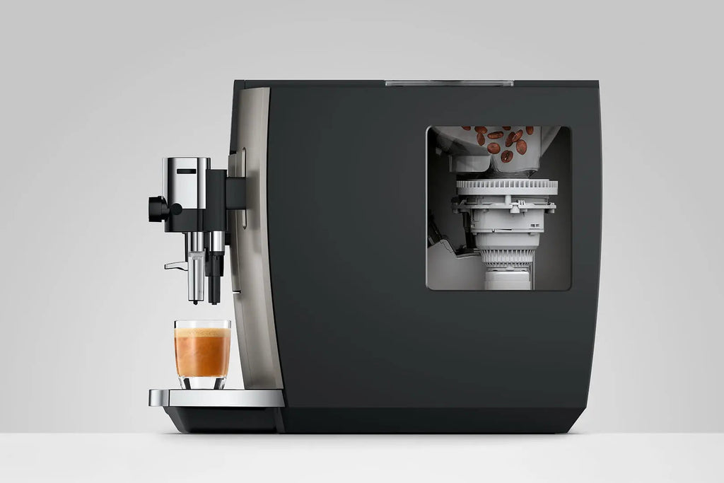 The Kitchen Table Jura E8 Midnight Silver automatic coffee machine showing internal bean grinder and coffee extraction