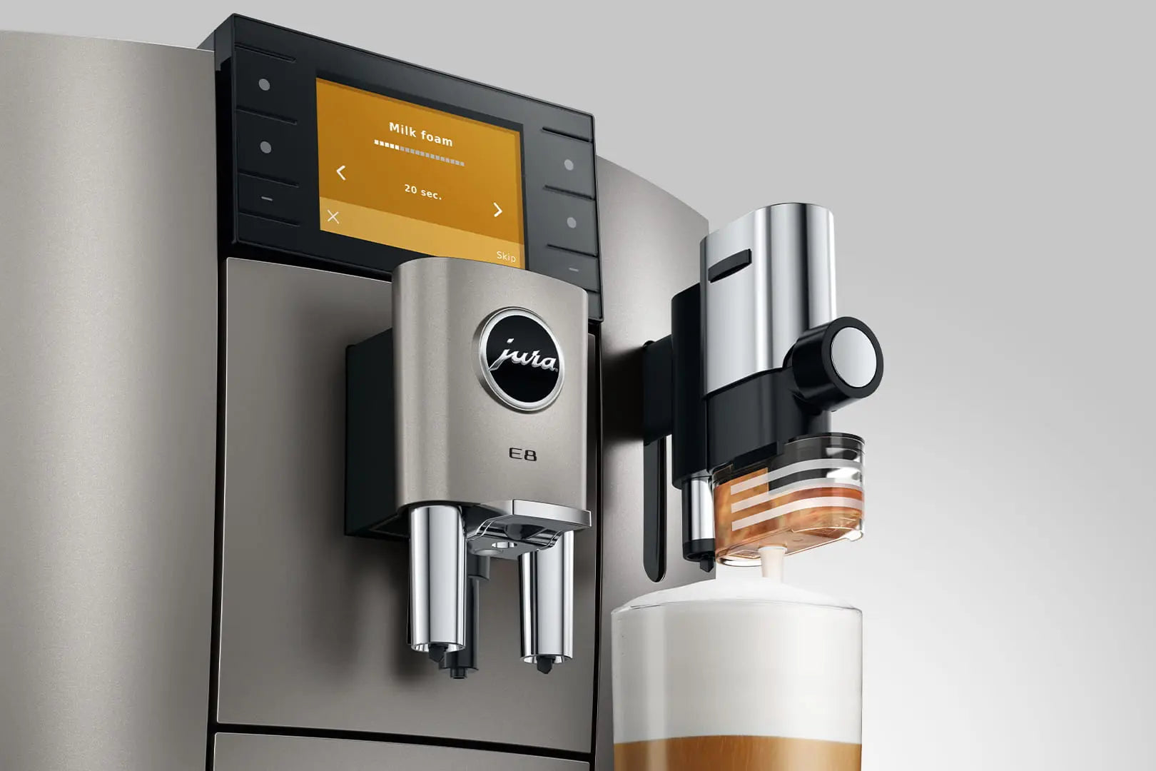 The Kitchen Table Jura E8 Midnight Silver automatic coffee machine dispensing milk foam into a glass.