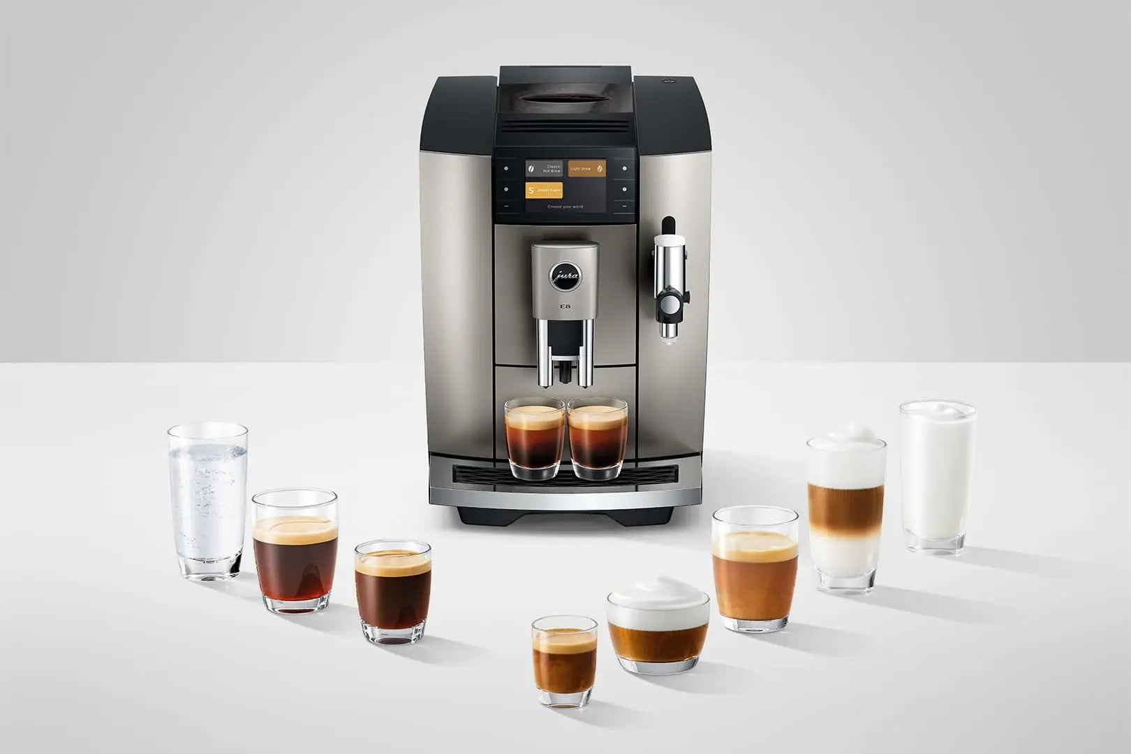 The Kitchen Table Jura E8 Midnight Silver automatic coffee machine with various coffee drinks in glasses on a table.