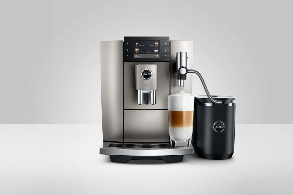The Kitchen Table Jura E8 Midnight Silver automatic coffee machine with a glass of layered latte and milk frother