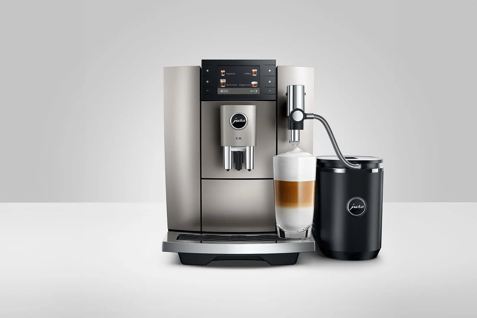 The Kitchen Table Jura E8 Midnight Silver automatic coffee machine with a glass of layered latte and milk frother