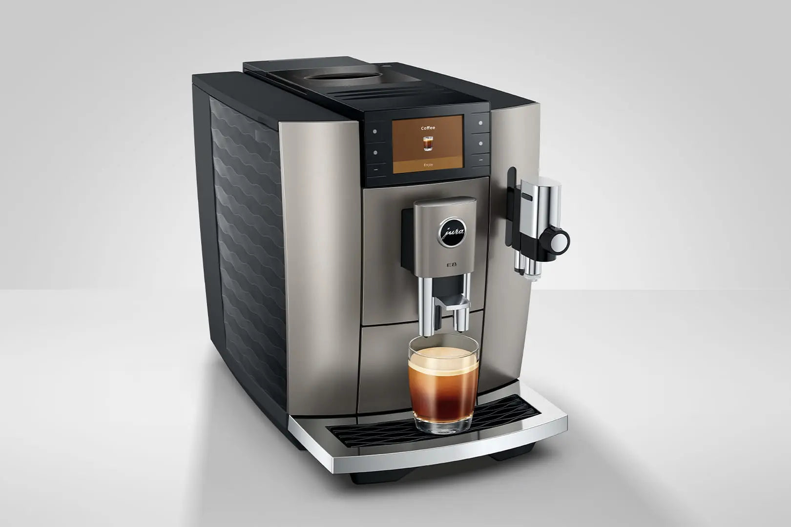 The Kitchen Table Jura E8 automatic coffee machine in Midnight Silver with a digital display and glass of espresso.