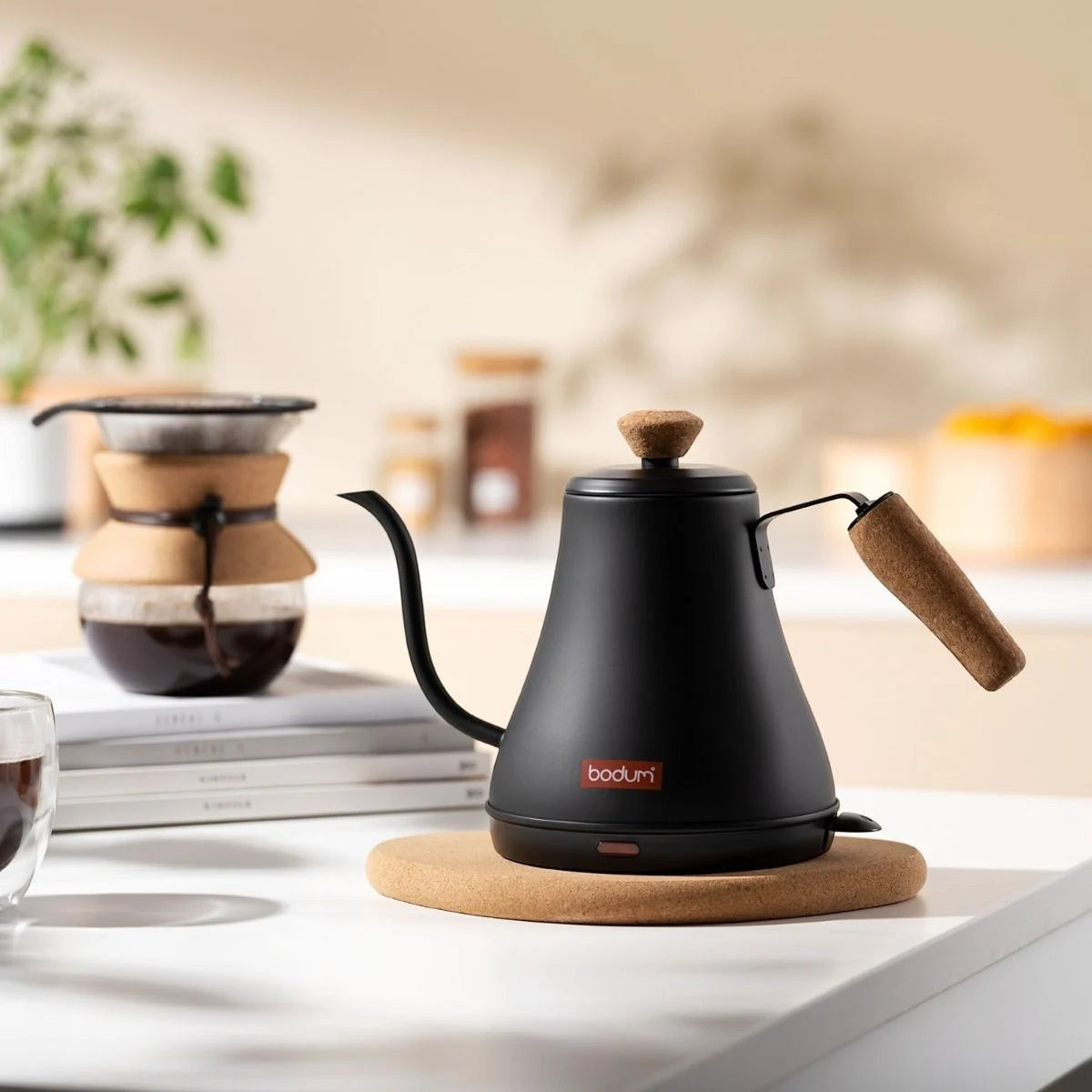 The Kitchen Table MELIOR electric gooseneck kettle in matte black with a sustainable cork handle on a kitchen counter.