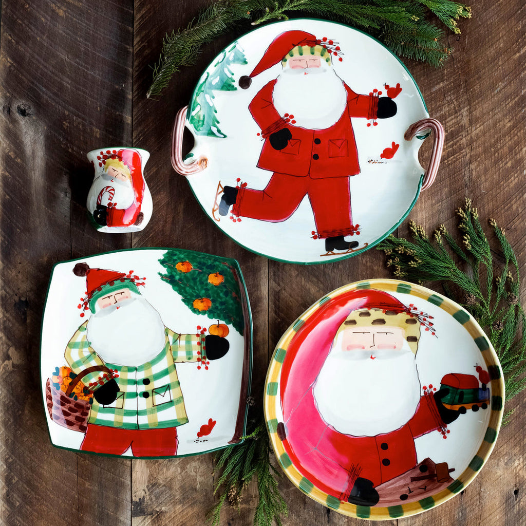 The Kitchen Table Old St. Nick ceramic holiday dinnerware set featuring hand-painted Santa Claus designs on rustic wood
