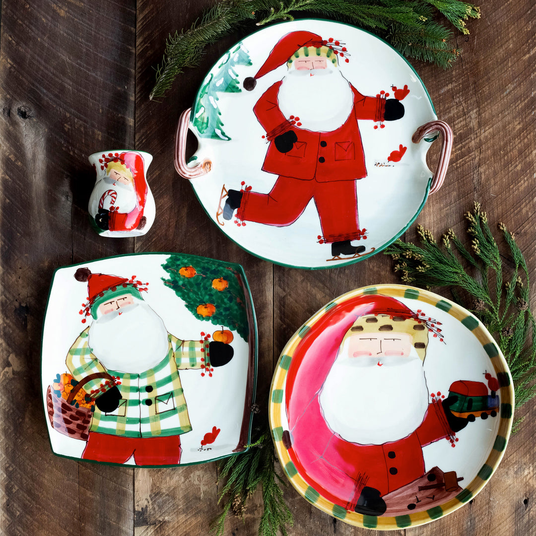 The Kitchen Table Old St. Nick ceramic holiday dinnerware set featuring hand-painted Santa Claus designs on rustic wood