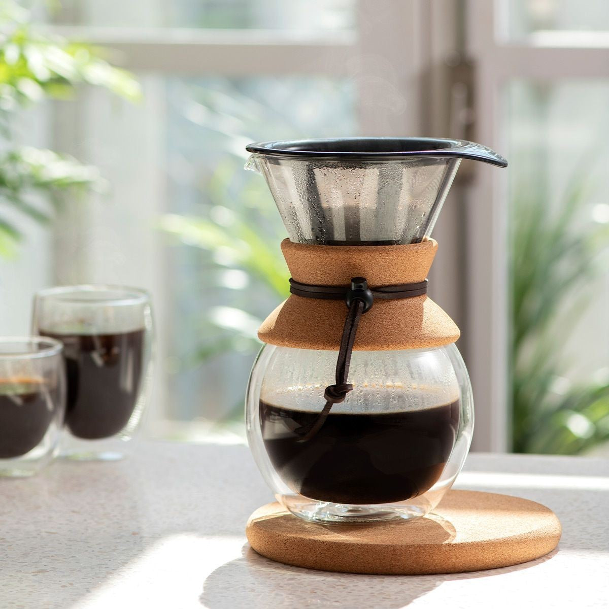 The Kitchen Table 8-cup pour over coffee maker with borosilicate glass carafe, stainless steel filter, and cork band.
