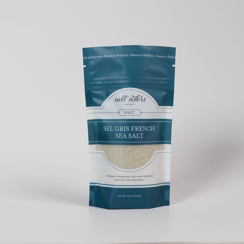 The Kitchen Table Sel Gris French sea salt in a teal stand-up pouch with a clear window showing grey mineral salt.