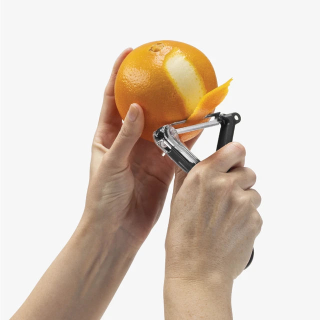 The Kitchen Table Dreamfarm Sharple Y-Peeler with self-sharpening blade peeling a red with ergonomic black handle