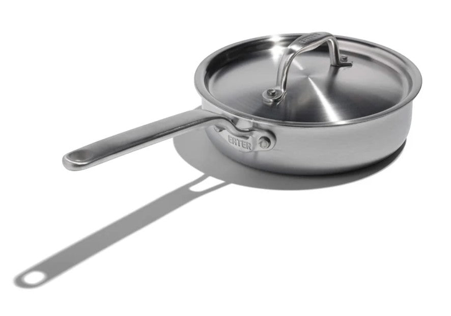 The Kitchen Table 1.5 quart stainless steel mini saute pan with a matching lid and long handle on a white background.