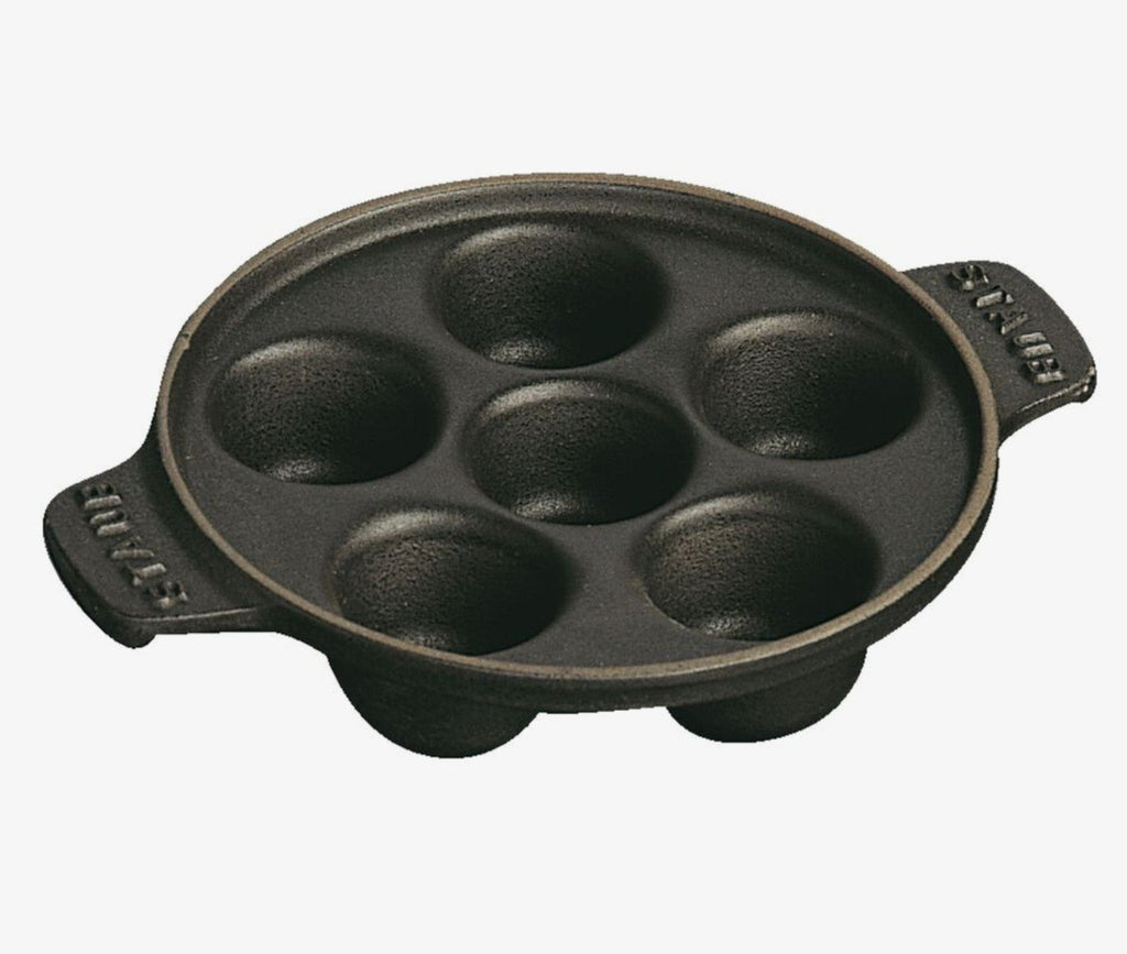 The Kitchen Table Staub cast iron escargot dish with six holes for cooking and serving snails.