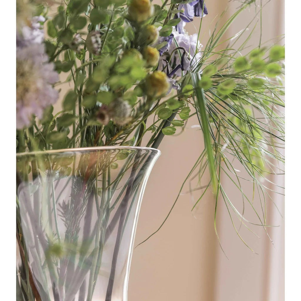 The Kitchen Table Weston large clear glass vase with a flared opening filled with a lush arrangement of wildflowers.
