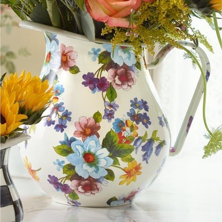 The Kitchen Table white enamel pitcher featuring a vibrant floral pattern filled with fresh flowers.